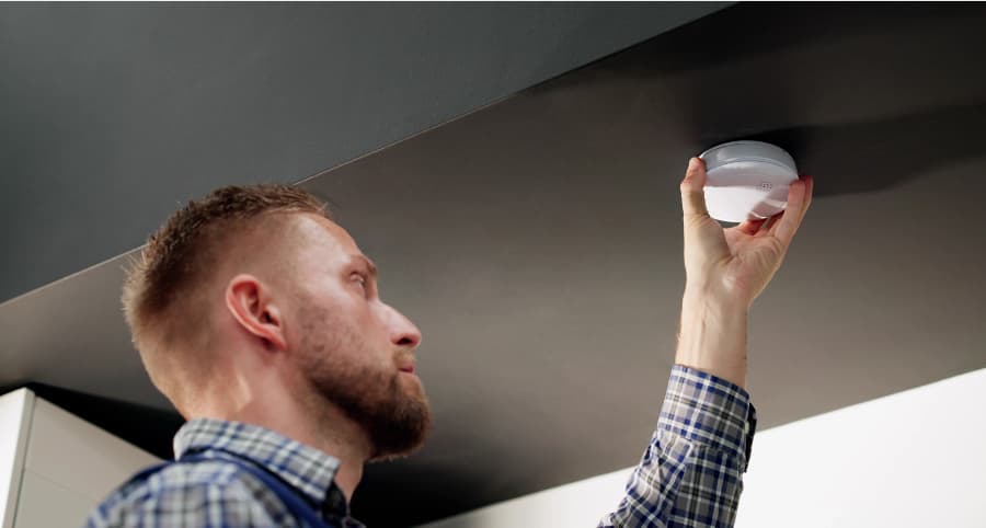 Man installing smoke detector on ceiling of home